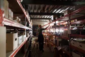 A man in a yellow beanie looks for an item on industrial shelving in a depot.