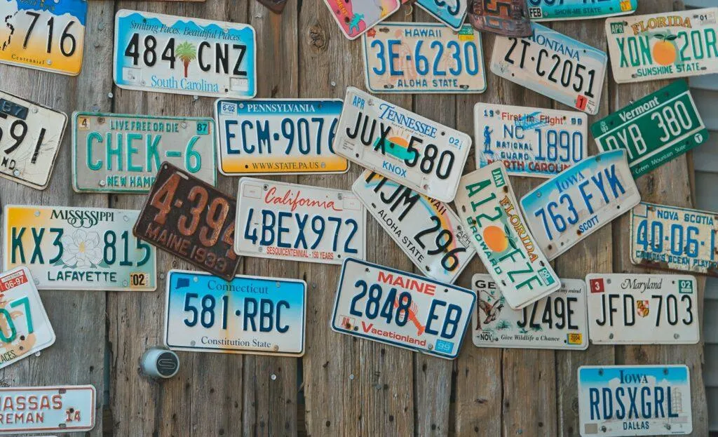 A wall holds vehicle license plates from different US states.