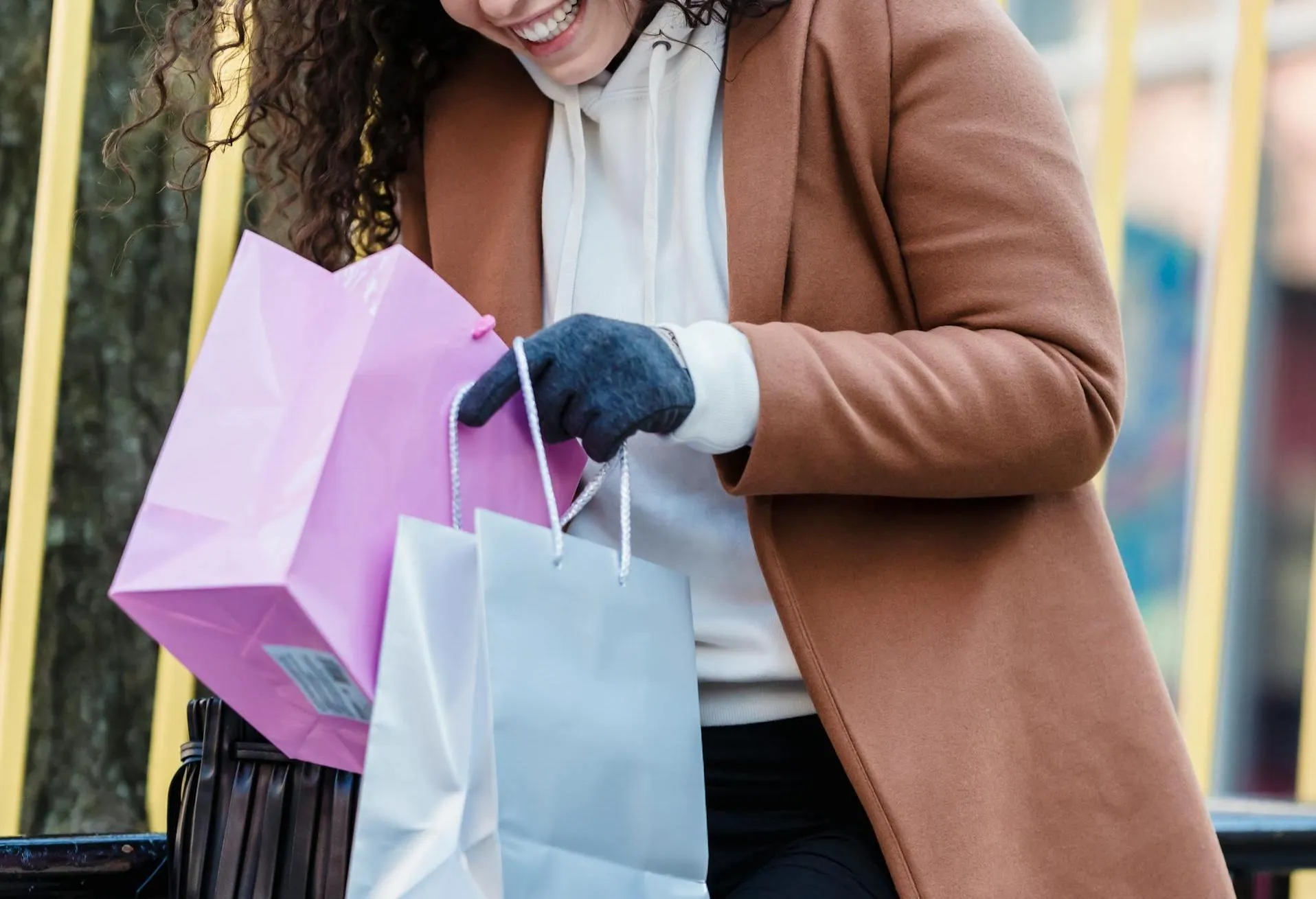 A woman looks in her shopping bags on the street.